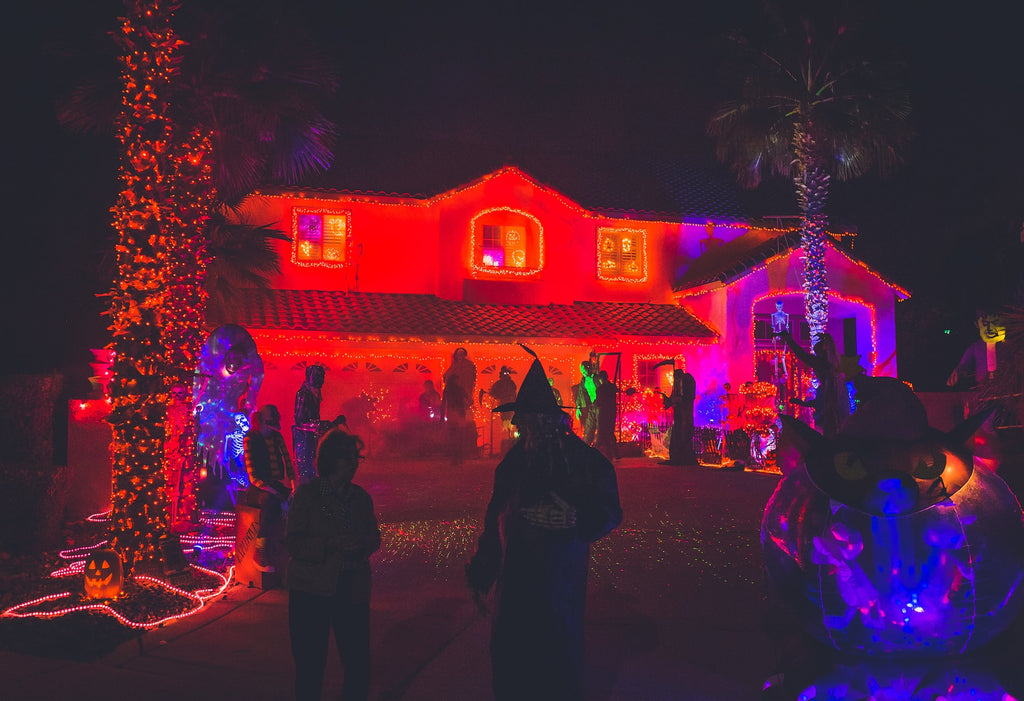 people in costumes stand in front lawn of decorated house