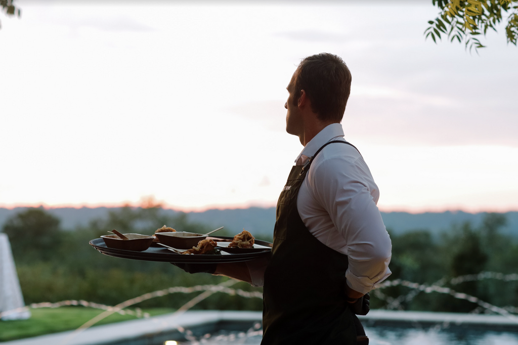 Man holding plate of appetizers overlooking sunset