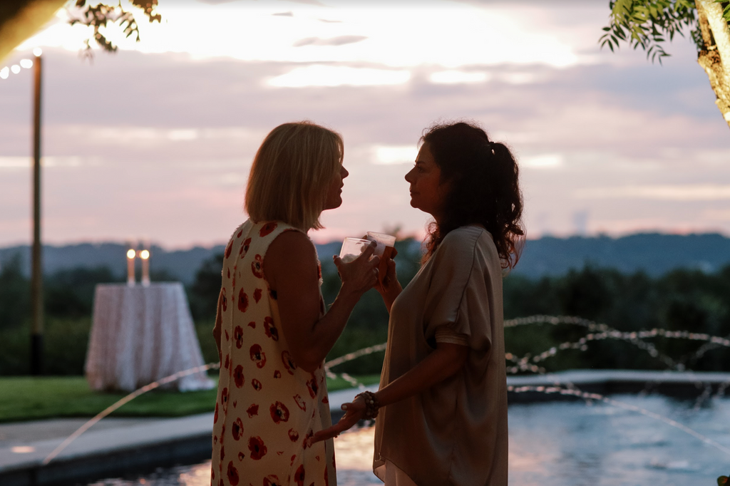 two women talking next to a pool overlooking sunset