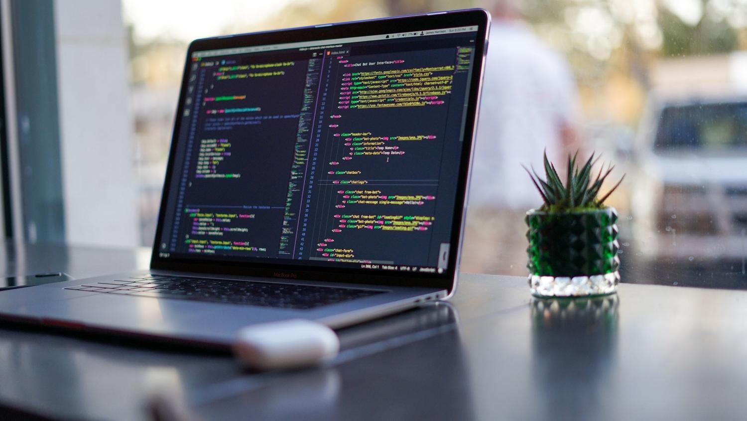 Laptop met code op het scherm geplaatst op een tafel naast het raam