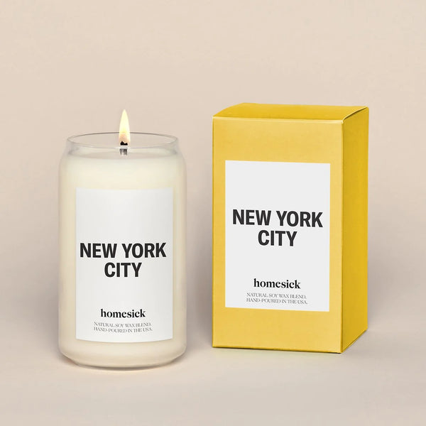Een brandende sojakaars en het doosje waarin de kaars verpakt zit bij de aankoop. De kaars is van het model New York City en wordt gemaakt door het Amerikaanse merk Homesick.