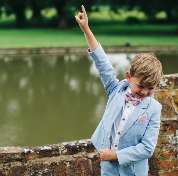 A Guide to Page Boy Fashion and Special Wedding Roles navy blue suit and dusty pink bow tie