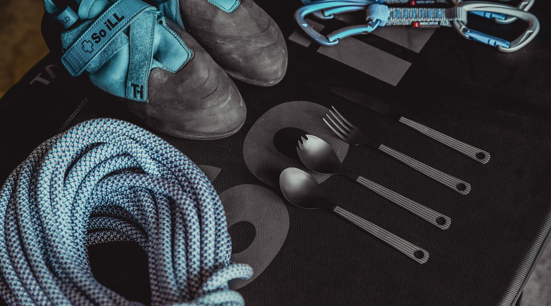 So iLL x On The Roam cutlery shown on a crash pad Distribution brush 2.0 is shown on a climbing mat with climbing chalk