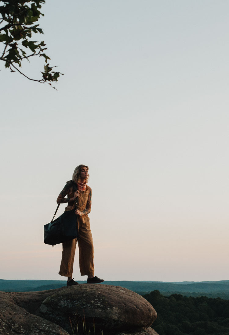 A woman carries the 45 liter black dirtbag on a climbing trip