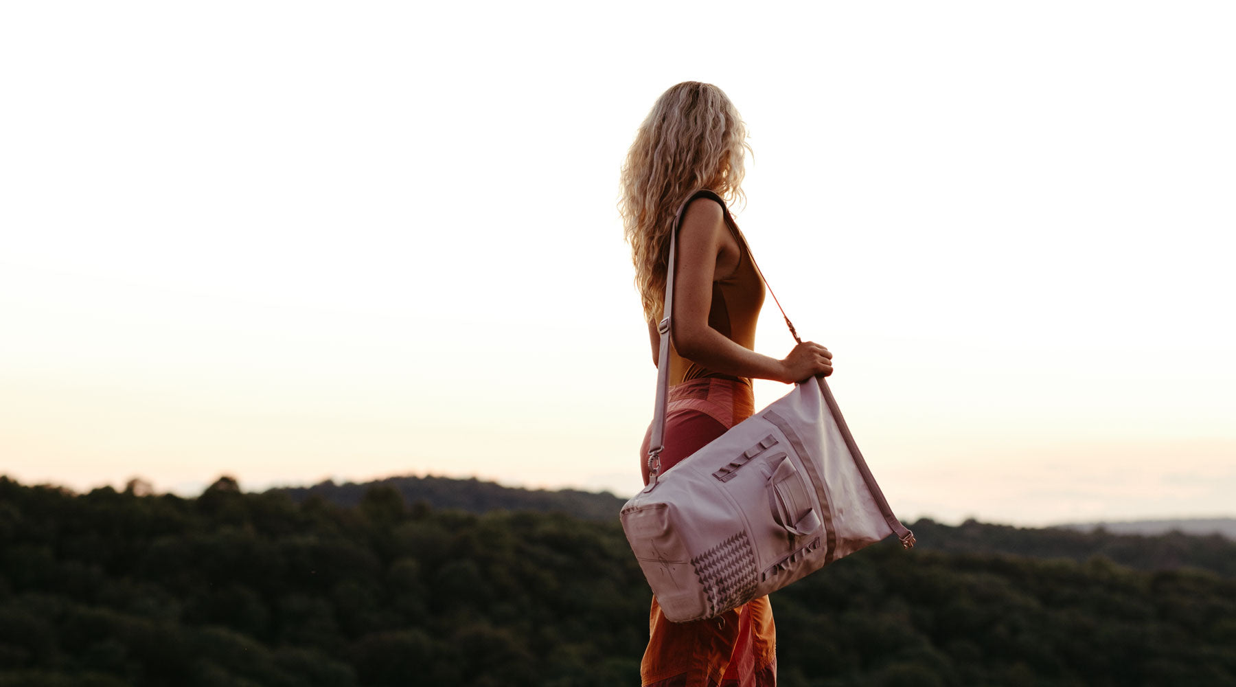 A woman carries the 45 liter black dirtbag on a climbing trip