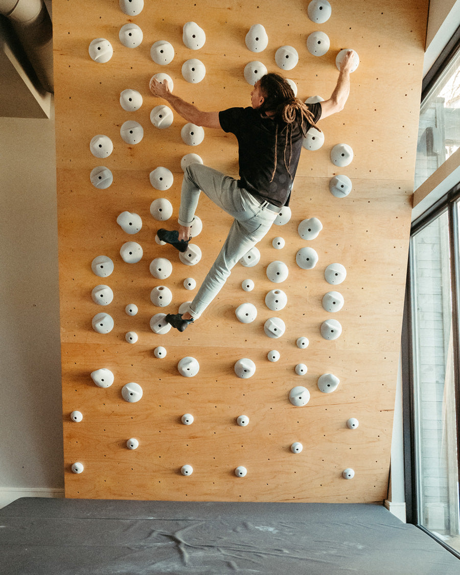 a man wears the so ill x on the roam black wolf polka dot tee while rock climbing