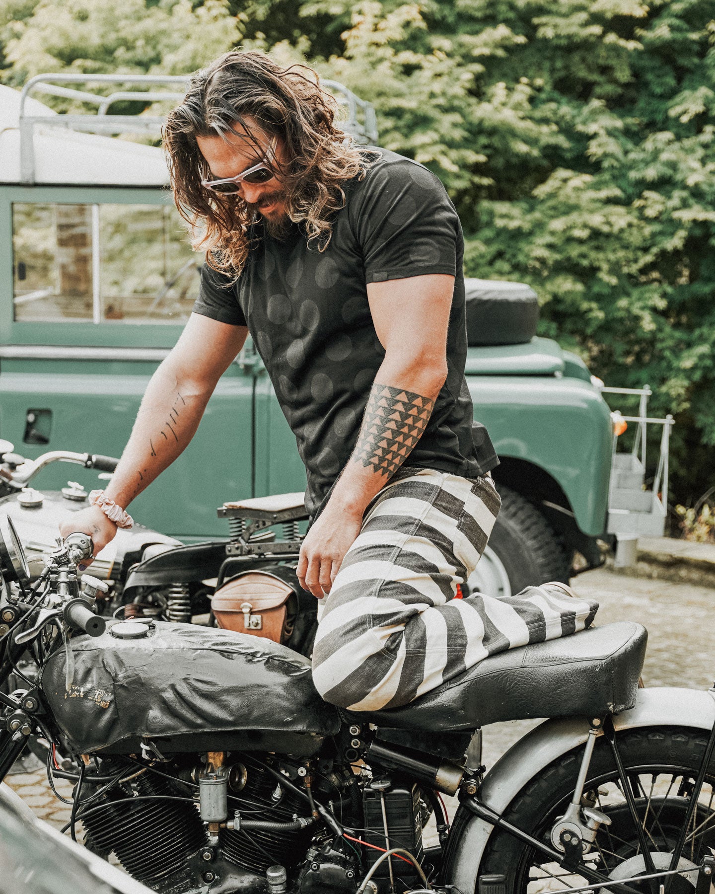 jason momoa the so ill x on the roam black wolf polka dot tee while checking out a motorcycle