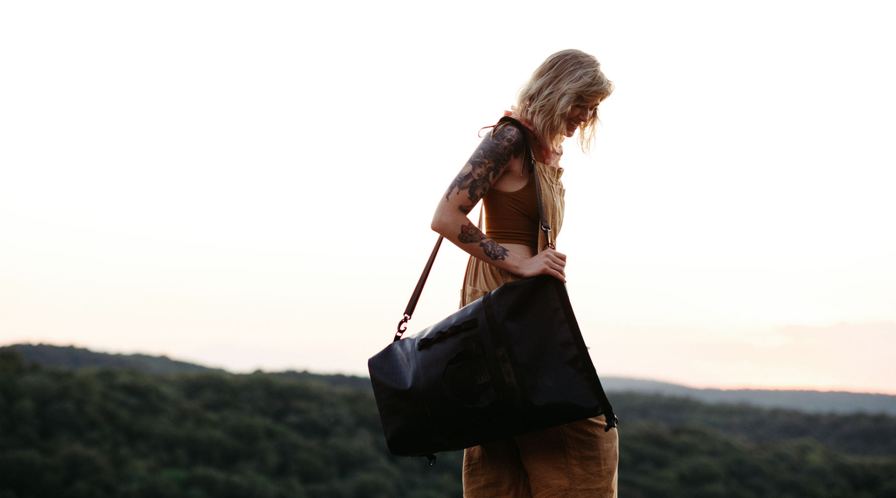 A woman carries the 45 liter black dirtbag on a climbing trip