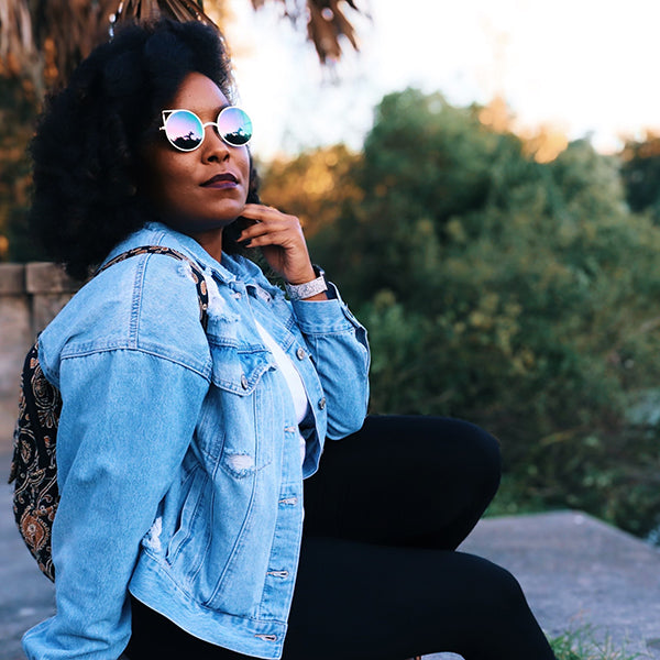 Girl on ground wearing jean jacket and sun glasses
