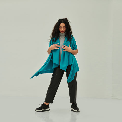 Woman in turquoise cape, pants and sneakers