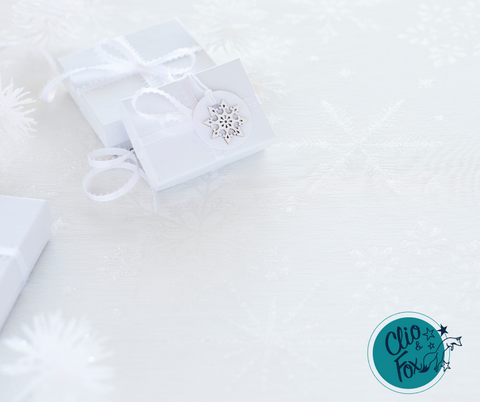 White gift boxes with ribbon on a white table clothe with silver snow flakes