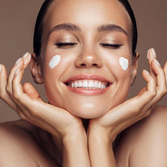 woman smiling holding hands by her face cream spread on her cheeks