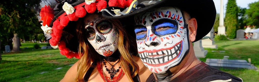 Un hombre y su esposa usando máscaras de calaveras como disfraz para un carnaval o Día de Muertos.