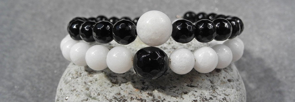 Two bracelets made of black and white beads which symbolize dualities.