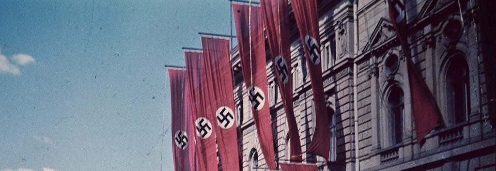 Flags of the Nazi regime with their swastika hung on the wall of an official building.