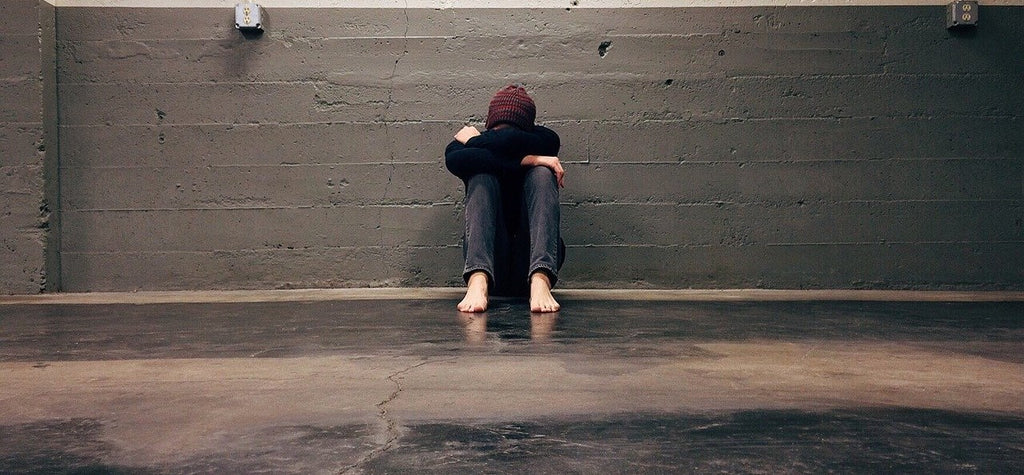 Man struck by bad luck, sitting looking sad in a parking lot