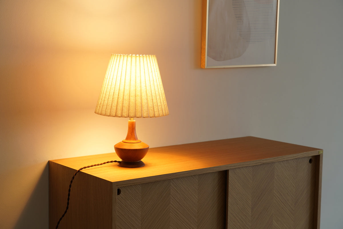プリーツ状のファブリックシェードが心地よい明かりを灯すナチュラルなテーブルライト（使用例点灯時）