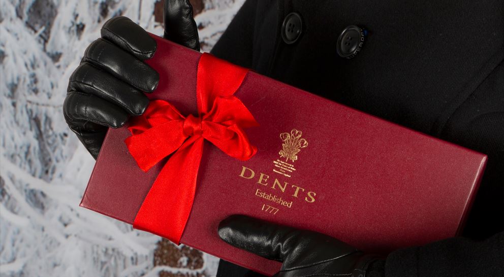 Man wearing leather gloves holding Dents gloves gift box with bow