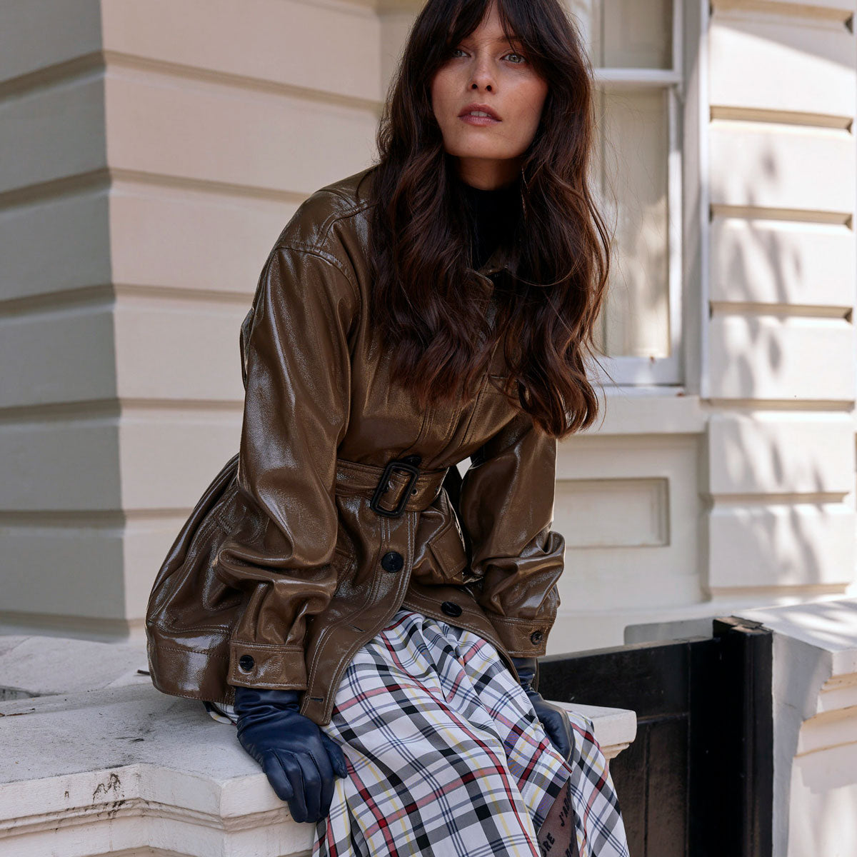 Woman wearing cashmere-lined leather gloves in navy with a brown coat in the city