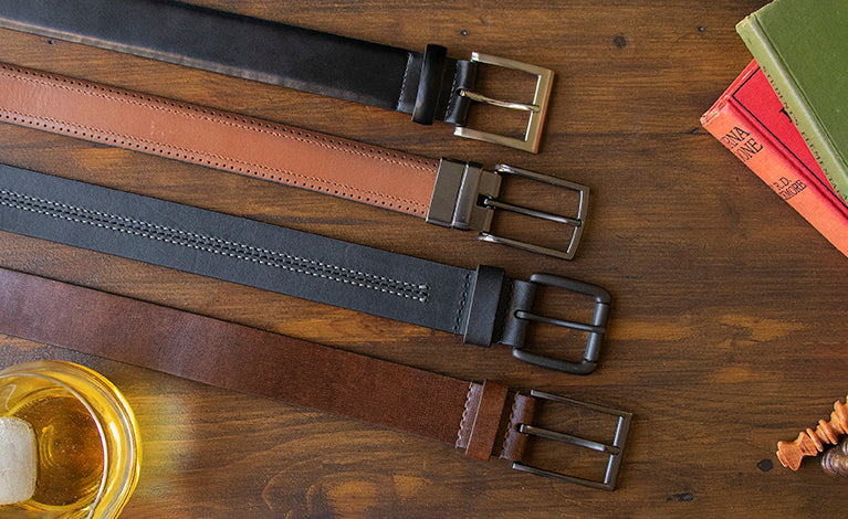 Mens leather belts in various colours laid out on a table