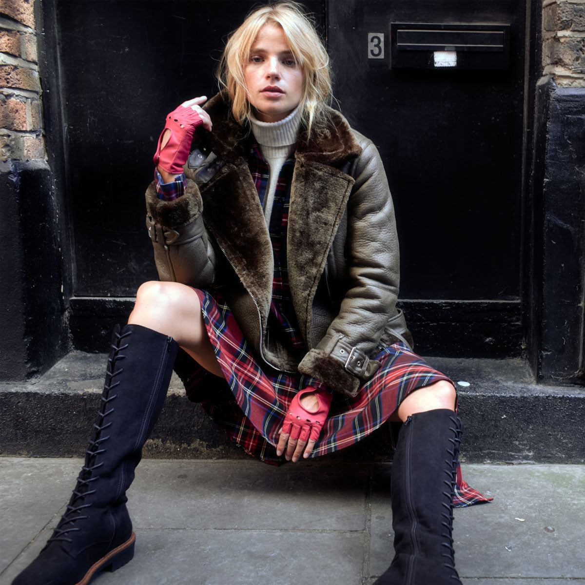 Woman wearing fingerless leather driving gloves in fuchsia