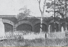 Brick arches with overgrown graves in the foreground