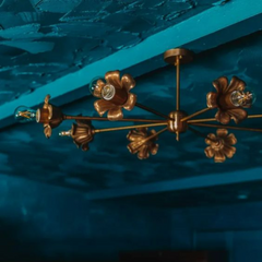 Brass floral chandelier in a teal blue room with a painted ceiling.
