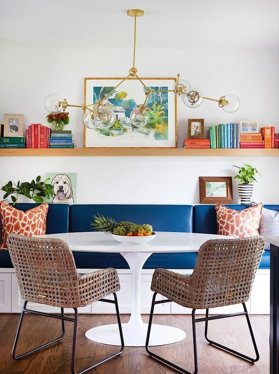 Dining room with an oversized brass and glass chandelier and built in bench with pedestal table