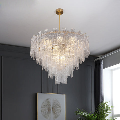 conical multi tier gold finish frosted glass chandelier hanging against gray wall panel background