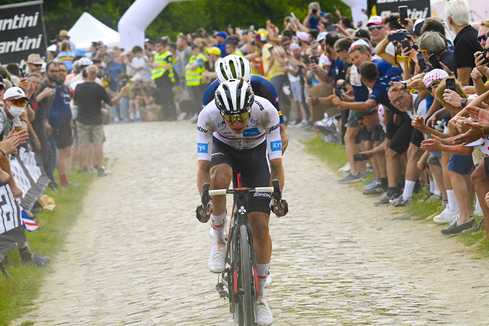 Tadej Pogacar corriendo sobre adoquines en el Tour de Francia
