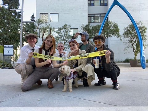 A group with a dog at a team building event in the USA. They are holding some police tape and crouching on the ground with the dog.