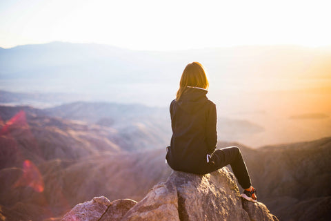 woman sitting in the mountains watching sunset