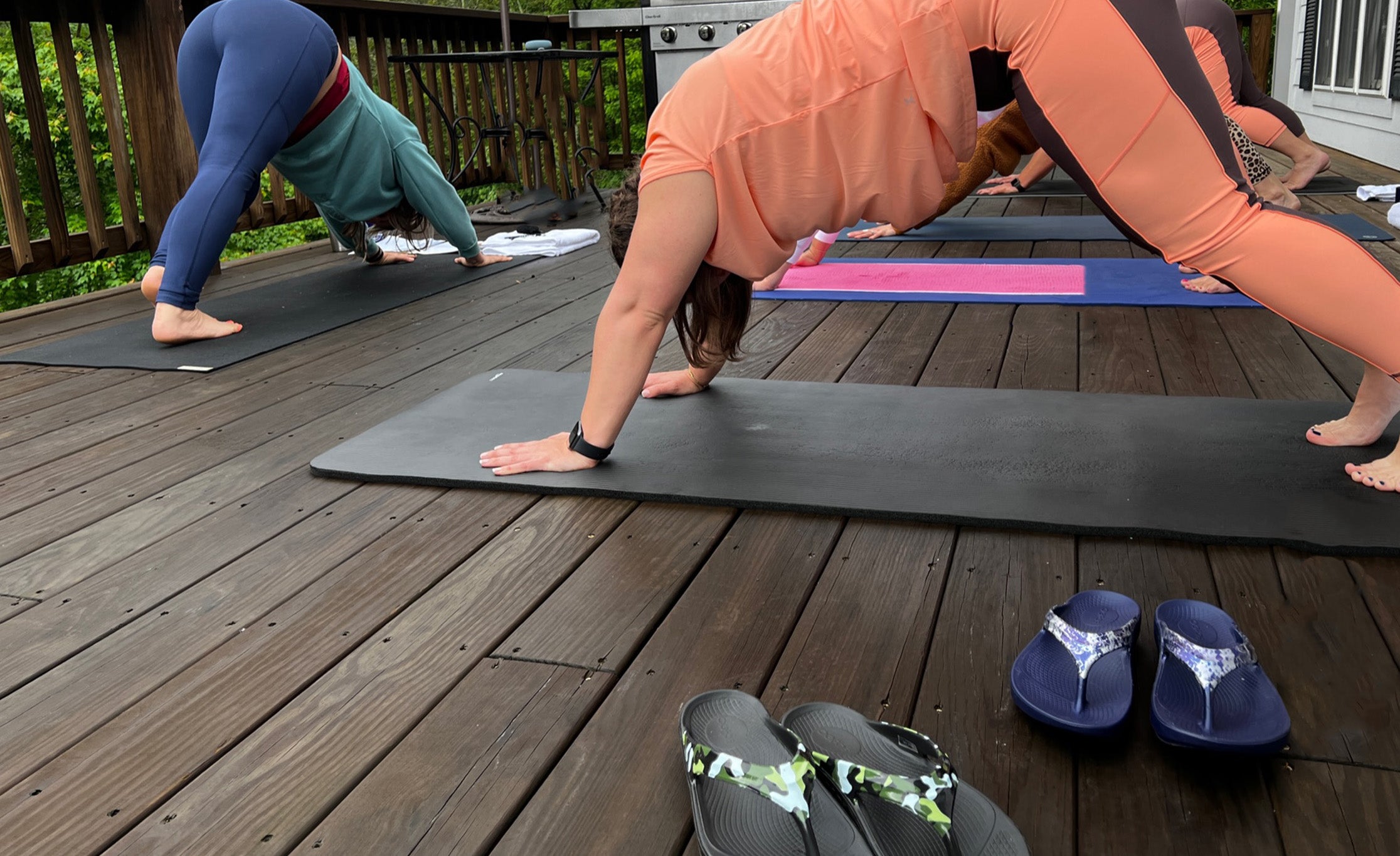 Two women doing yoga behind OOFOS shoes