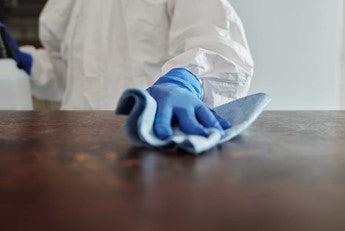 Person cleaning an office desk with a microfibre cloth