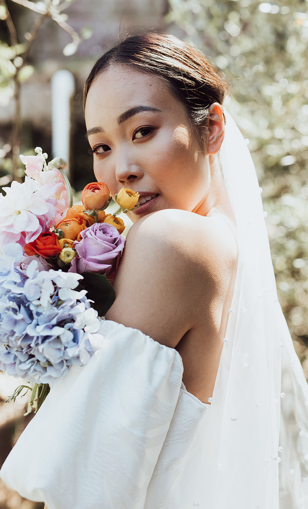 Bride holds garden bouquet looking over her shoulder