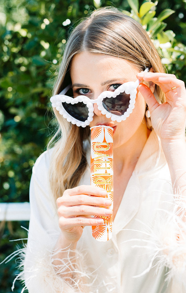 Bride wears heart sunglasses and eats a aperol spritz flavoured gelato pop.