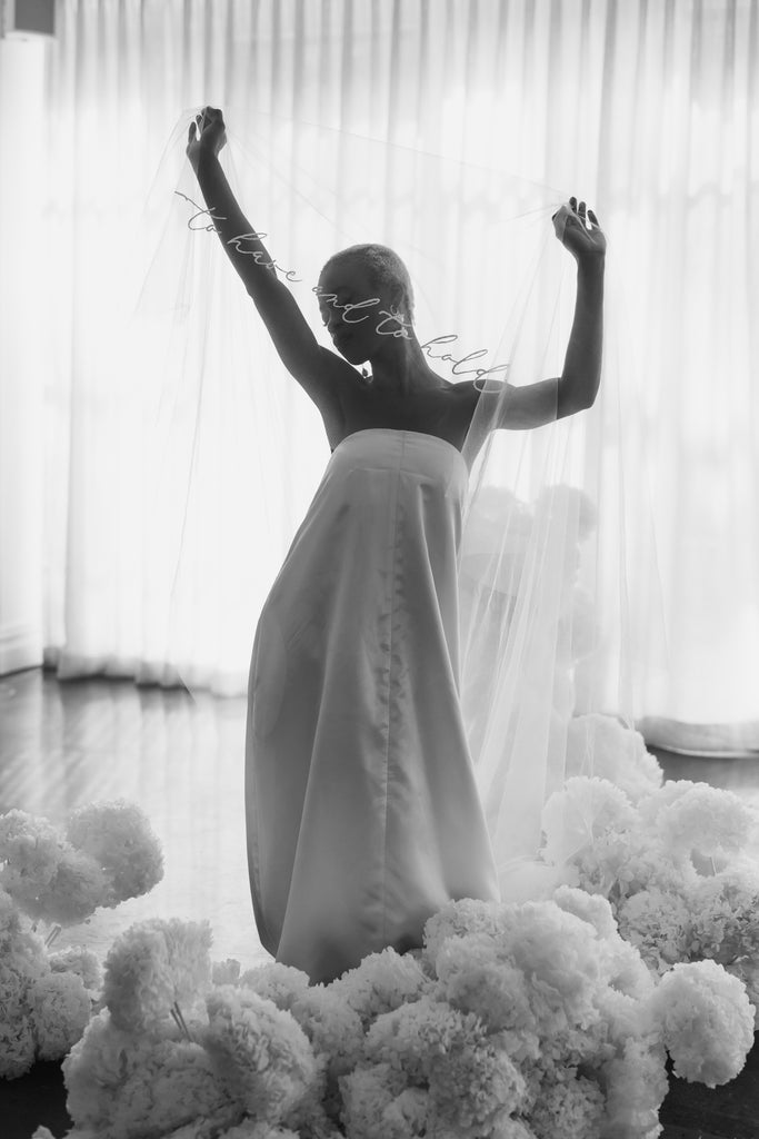 Bride wears a to have and to hold wedding veil and stands in a warehouse venue with a en masse floral installation