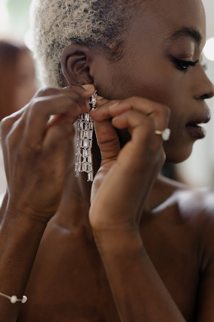 Bride puts on her long crystal bridal earrings 