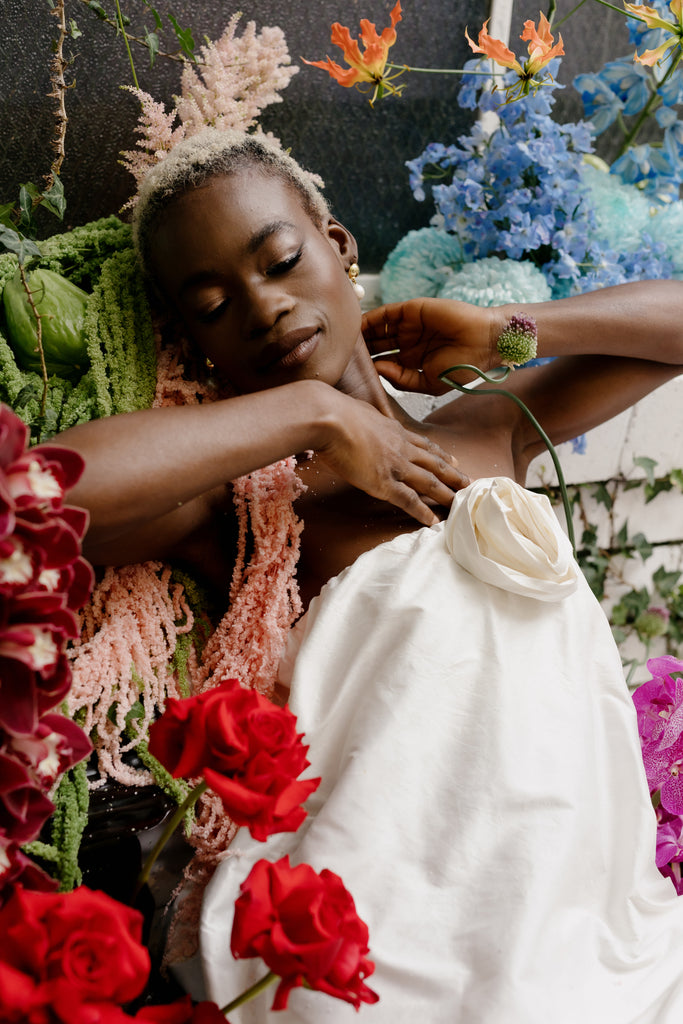 Bride sits surrounded by florals in courtyard setting 