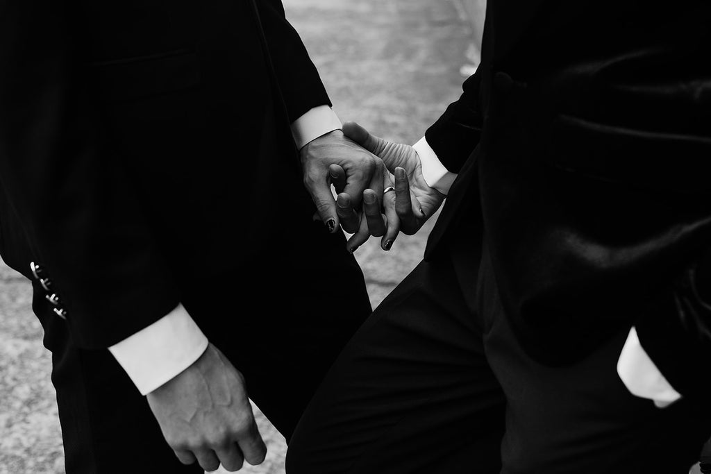 same sex couple holds hands at their wedding 