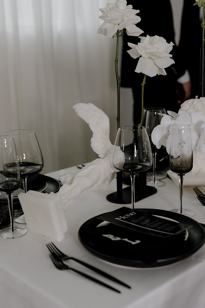 Angel candle lays on its side on monochrome styled table.