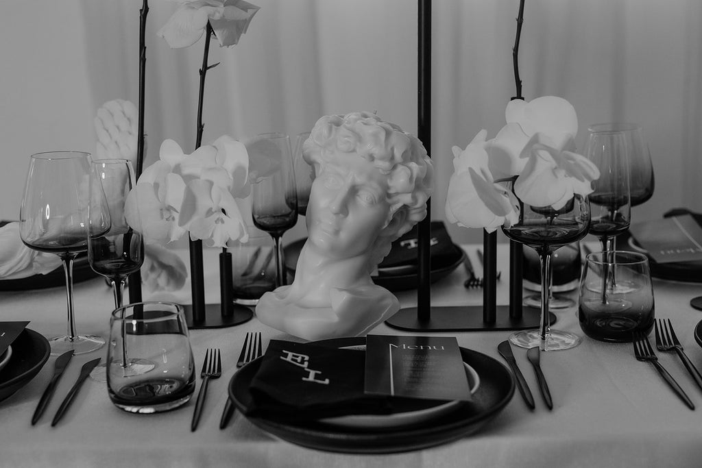 monochrome styled table with orchids and roses, bust candle lays on it's side