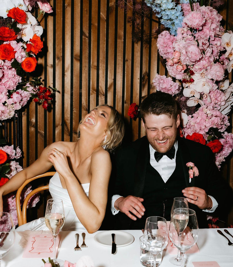 Michelle Andrews and husband Mitchell Rees laughing whilst seated at their reception dinner