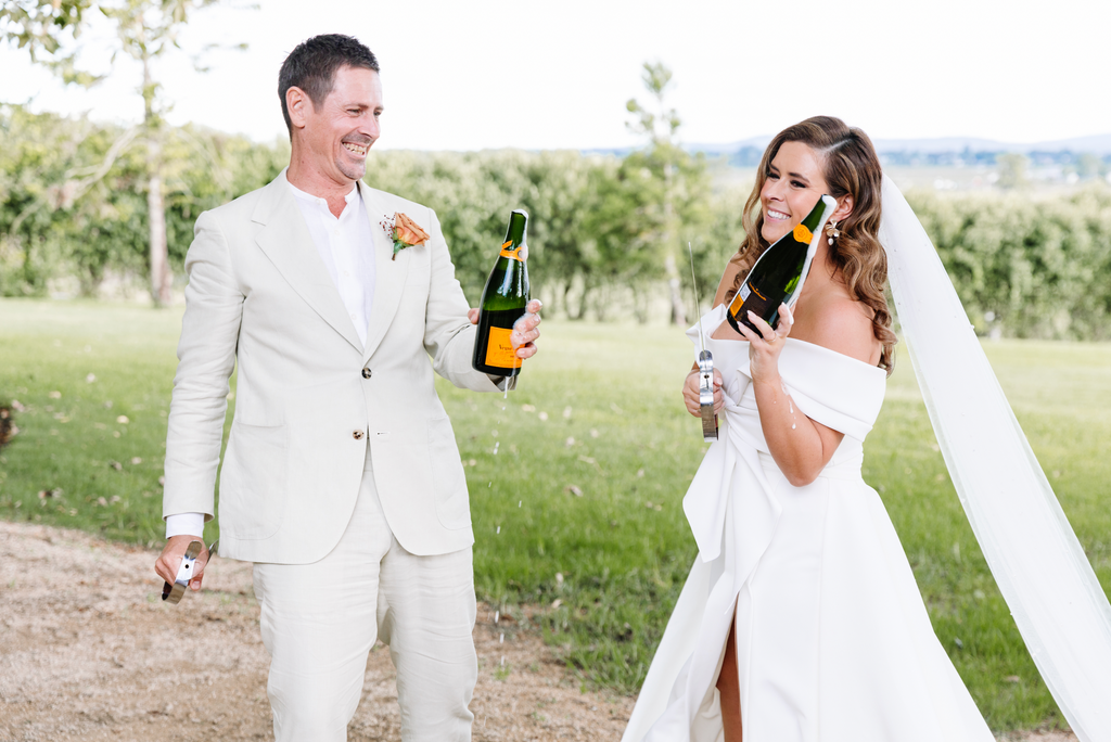 Bride and groom pop champagne post wedding ceremony