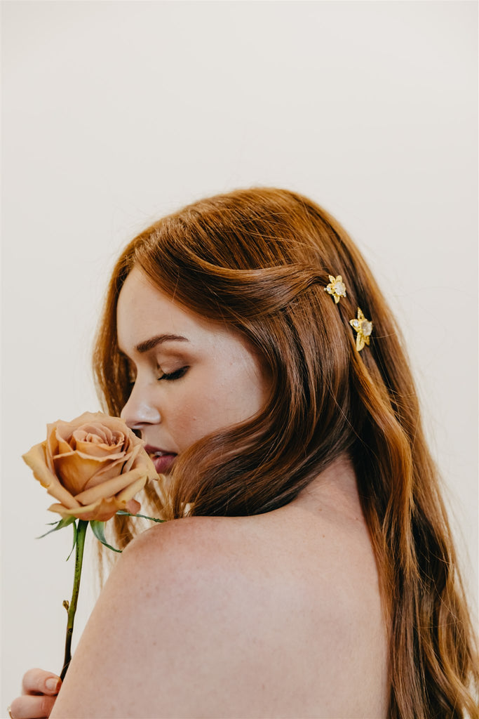 Bride with gold hair clips in her red hair smells a toffee rose