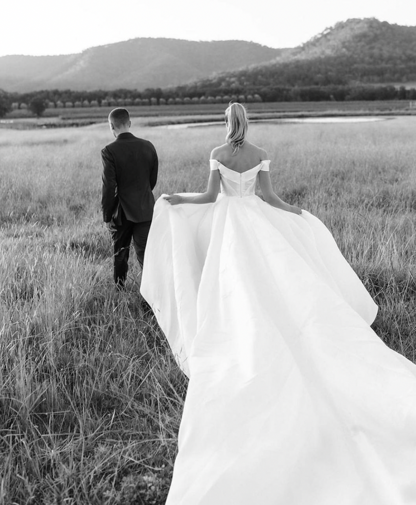 Black and White Photo of Natalie Roser and Harley Bonner Wedding. Couple with backs to the camera walking away into the estate.