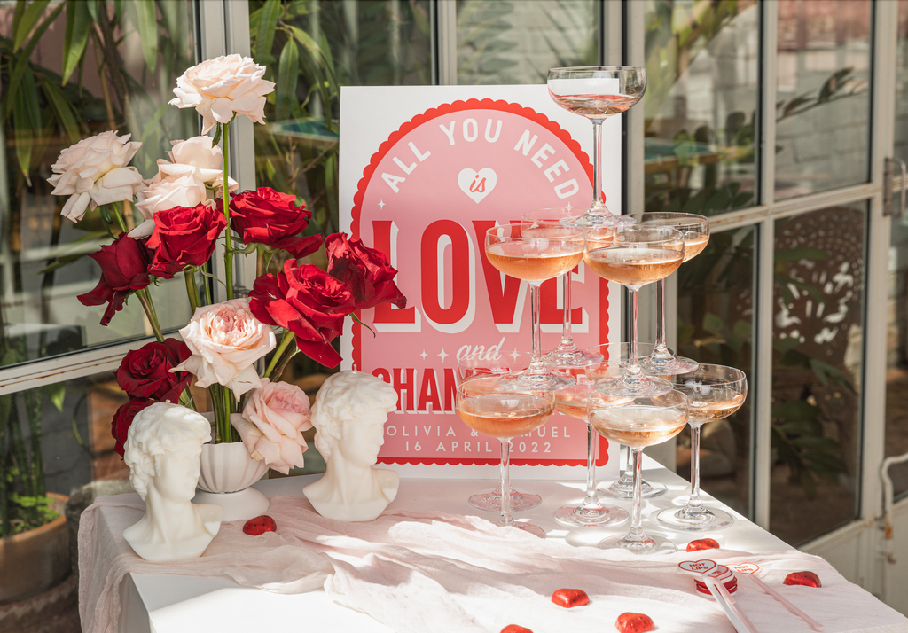 Tower of rose glasses sits in front of a red and pink sign, roses and david bust candles