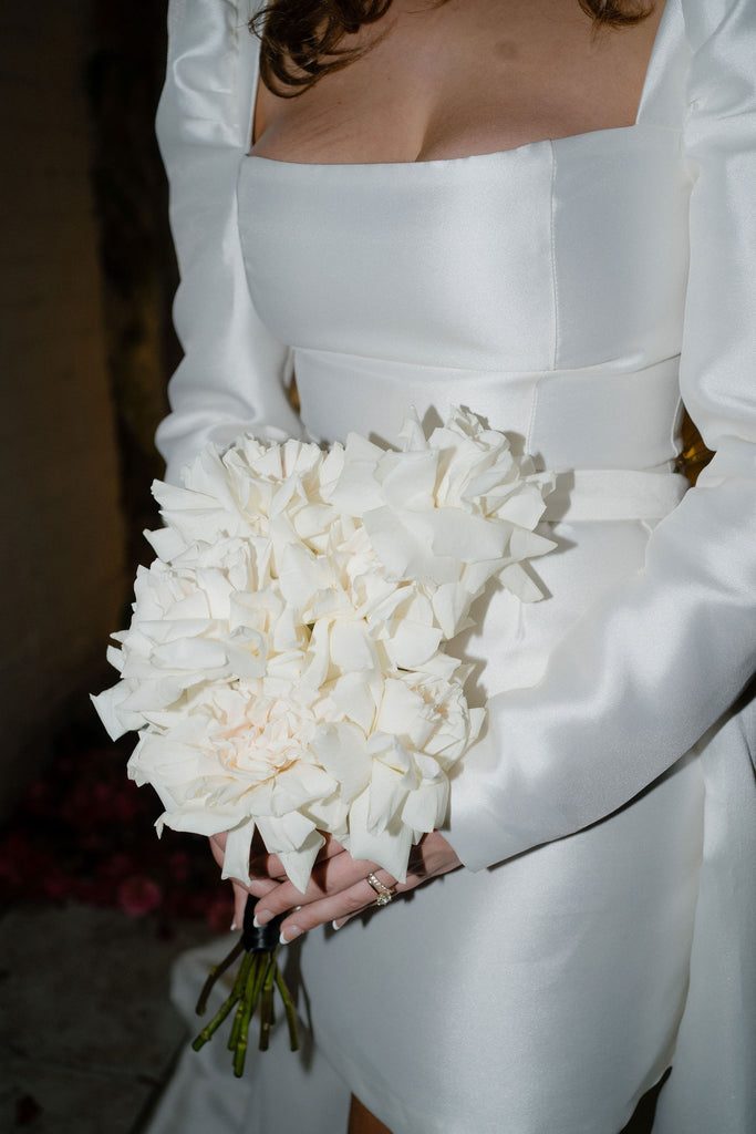 Bride holds bouquet of white roses in photo taken with flash photography