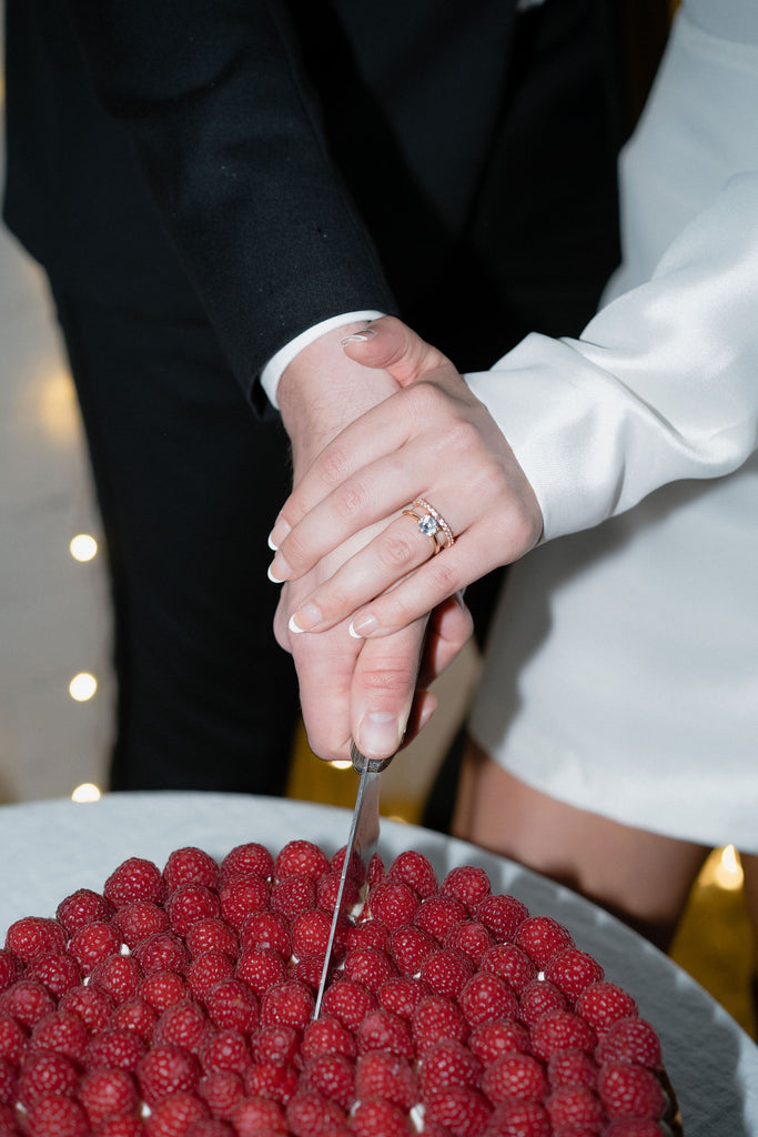 Bride and Groom cut a giant raspberry wedding cake, you see the brides wedding rings.