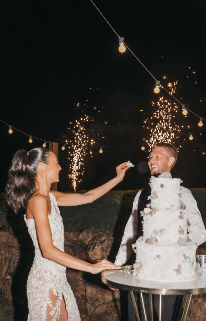 Tayla Damir and Nathan Broad eating their wedding cake with fireworks in the background